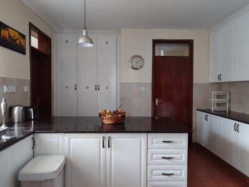 une cuisine avec des placards blancs et un comptoir noir dans l'établissement Lantana Gardens B2 & B8 Apartment, à Nairobi