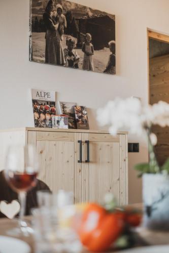 a table with a glass of wine and a picture on the wall at Ragitt Stodl Ferienwohnungen in Vols am Schlern