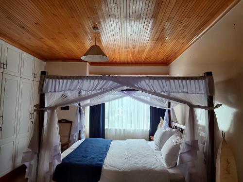 a bedroom with a canopy bed with a window at Lantana Gardens B2 & B8 Apartment in Nairobi