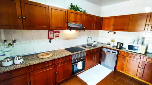 uma cozinha com armários de madeira e um lavatório em Casa Gina, with views to Funchal Bay em Funchal