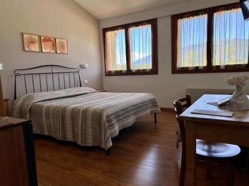 1 dormitorio con cama, mesa y ventanas en Country House La Montagnola, en Valdobbiadene