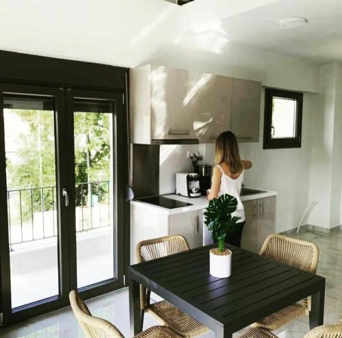 a woman standing in a kitchen with a table at ACTA Luxury Rooms in Nikiti