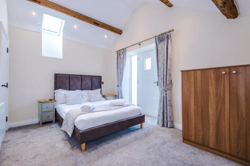 a bedroom with a large bed and a wooden cabinet at Unique 2-bed barn in Beeston by 53 Degrees Property, ideal for Families & Friends, Great Location - Sleeps 4 in Beeston