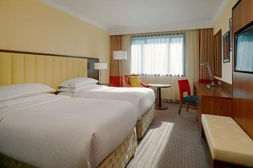 a hotel room with two beds and a desk at Sheraton Zagreb Hotel in Zagreb