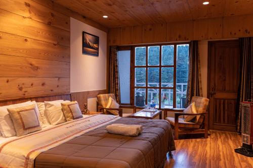 um quarto com uma cama grande num quarto com paredes de madeira em THE CONIFER em Manali