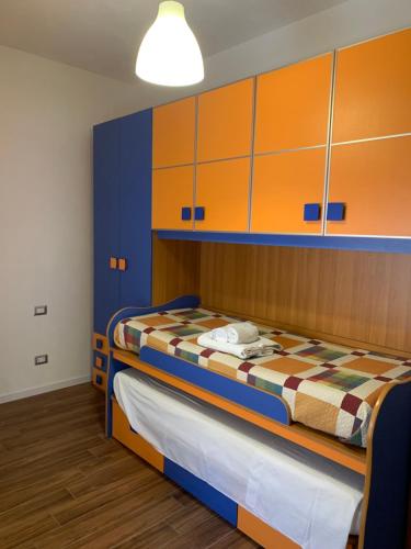 a bedroom with a bed with orange and blue cabinets at CASA VACANZE MAZARA in Mazara del Vallo