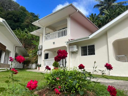 a white house with red flowers in the yard at Paul's Residence in Mahe
