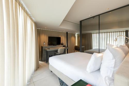 ポルトにあるPorto Royal Bridges Hotelのベッド、デスク、テレビが備わるホテルルームです。