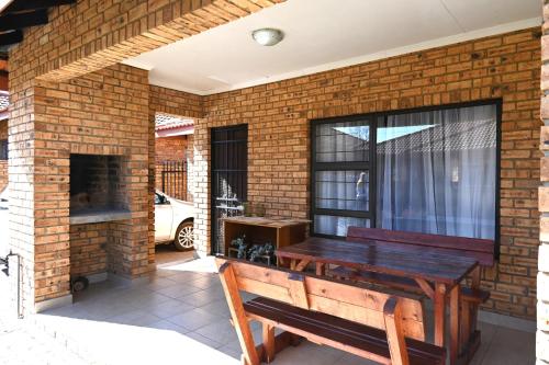 a patio with a wooden bench on a brick wall at Summersun Village in Parys