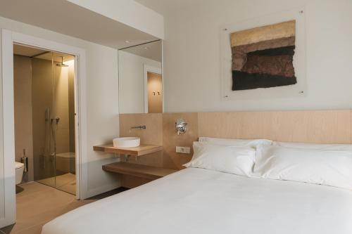 a bedroom with a white bed and a bathroom at Hotel Santa Ana Tudela in Tudela