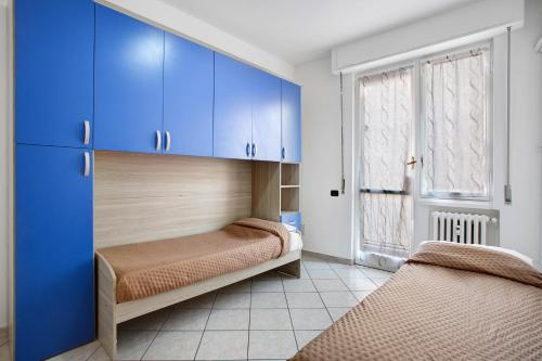 two beds in a room with blue cabinets and a window at Easy Home vicino a Milano e Monza in Nova Milanese