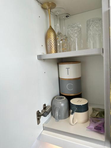 a shelf with cups and other items on it at Comfort Stay Apartment in Haywards Heath