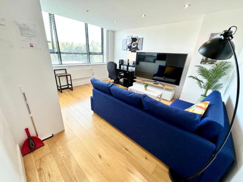 a living room with a blue couch and a tv at Comfort Stay Apartment in Haywards Heath