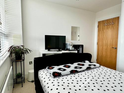 a bedroom with a bed with a black and white comforter at Comfort Stay Apartment in Haywards Heath