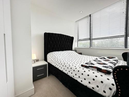 a bedroom with a bed with a black headboard and a window at Cosy Apartment Haywards Heath in Haywards Heath