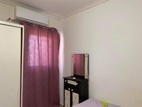 a bedroom with a purple curtain and a tv on a dresser at North coast in Alexandria