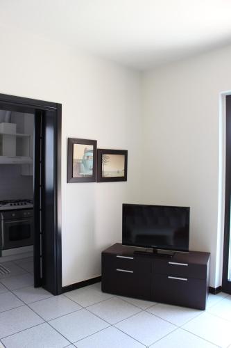sala de estar con TV de pantalla plana en una pared blanca en Casa Maria-Appartamento in Villa, en Ispra