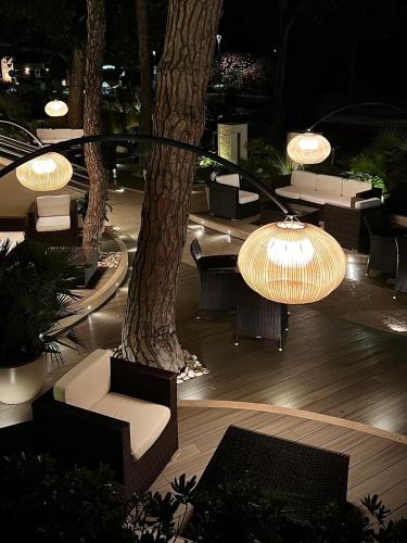 a patio with chairs and lights and trees at night at Hotel Mazzanti in Milano Marittima