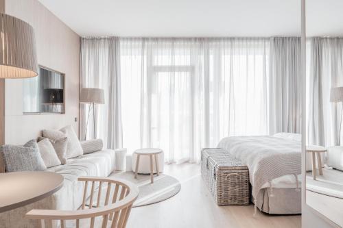 - un salon blanc avec un lit et un canapé dans l'établissement Nils am See, à Weiden am See