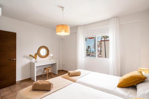 una camera bianca con un grande letto e uno specchio di Sur Suites Porlamar a Fuengirola