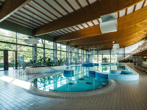 a large swimming pool in a building with windows at Hotel Kristal - Terme Krka in Dolenjske Toplice
