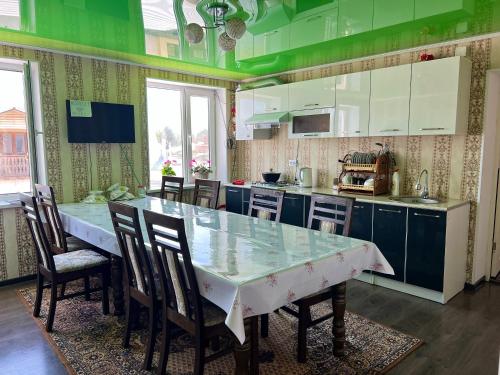 Kochkorka的住宿－MALIKA Guest House，厨房配有桌椅和绿色的墙壁