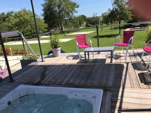 a hot tub on a deck with chairs and a table at AU POINT DE VUE DE LA ROCHE in Morey