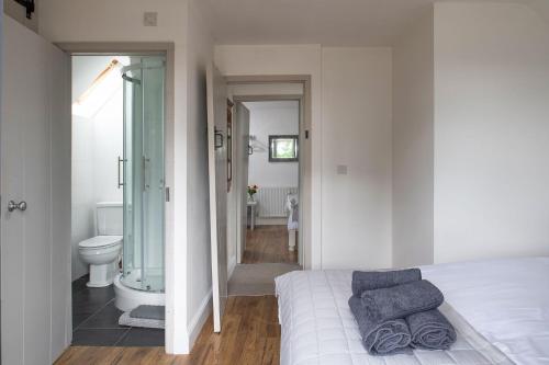 a bedroom with a bed and a bathroom with a shower at The Milking Parlour in Malmesbury