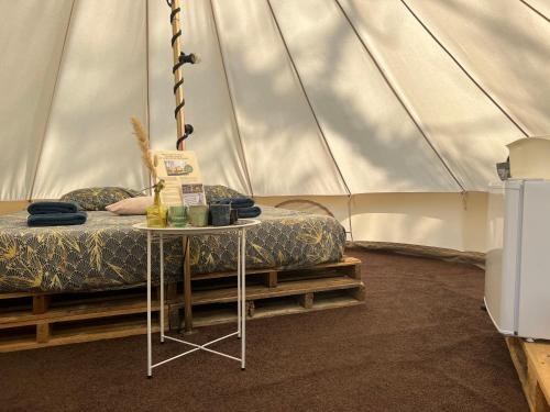Glamplodge met privé sanitair في Blesdijke: غرفة نوم بسرير وطاولة في خيمة