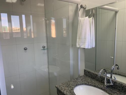 a bathroom with a sink and a shower with a mirror at Hotel Seven in Goiânia