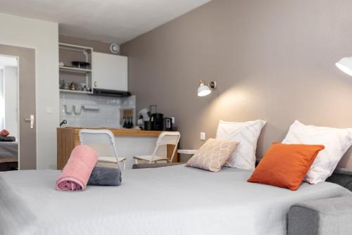 a bedroom with a bed with pillows and a kitchen at Les Terrasses de Rangueil : studio avec parking in Toulouse