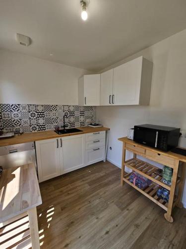a kitchen with white cabinets and a wooden table at Maison Le Bois Petit in Mouy