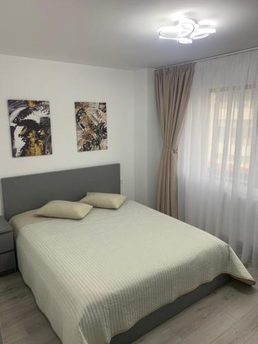 Habitación blanca con cama y ventana en New Apartment Trivale Park, en Piteşti