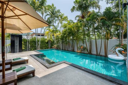 a swimming pool with an umbrella and an inflatable pool at Ban Bua Lux x MonthStayz Thailand in Rawai Beach