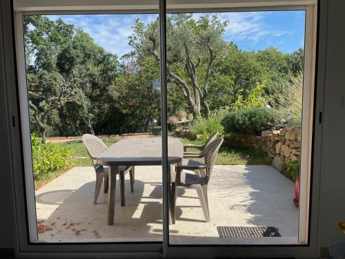 a table and chairs on a patio with a window at Cottage les Marjoris Tanneron in Tanneron