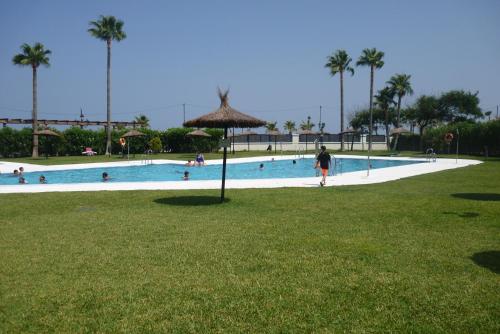 Una gran piscina con gente en un parque. en Beachfront 3 Bed Apt San Luis De Sabinillas, en San Luis de Sabinillas