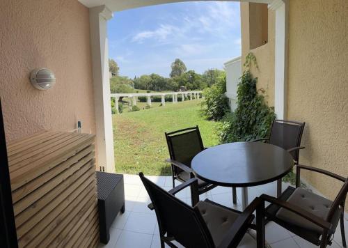a patio with a table and chairs and a view of a field at Appt Golfe de Saint-Tropez proche de la mer climatisé in Grimaud