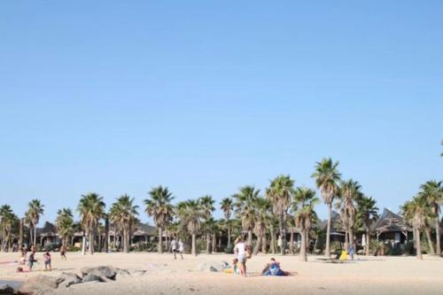 a group of people on a beach with palm trees at Appt Golfe de Saint-Tropez proche de la mer climatisé in Grimaud