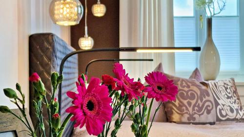 a vase filled with pink flowers next to a couch at Boutique Hotel POST ANDECHS in Andechs