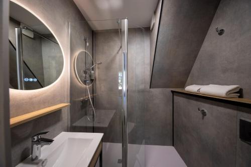 y baño con ducha, lavabo y espejo. en Hôtel-Restaurant Logis l'Aubrac Laguiole, en Laguiole