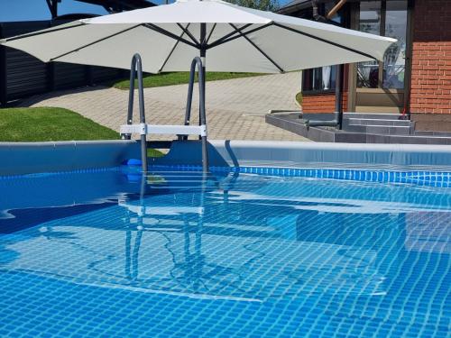 Grabrovnik的住宿－Kuća za odmor Family Ferlin，一个带遮阳伞和椅子的游泳池
