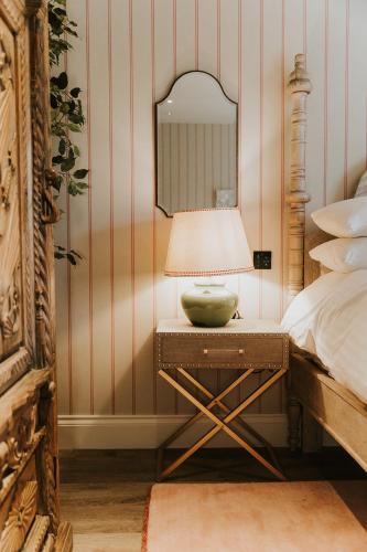 a bedroom with a table with a lamp and a mirror at The Tempus at Charlton Hall Estate in Alnwick