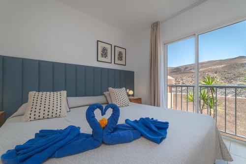 ein Bett mit zwei blauen Handtüchern in Herzform in der Unterkunft Villas Monte Solana in Morro del Jable