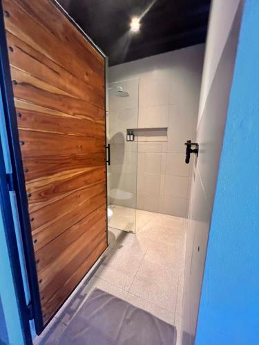 a bathroom with a shower and a wooden door at Rumah Kahyangan in Canggu