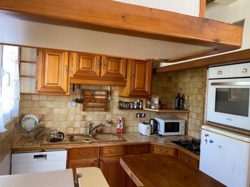 La cuisine est équipée de placards en bois, d'un évier et d'un four micro-ondes. dans l'établissement Maison de vacances au Pouliguen, au Pouliguen