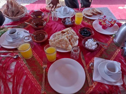 a table with plates of food and glasses of orange juice at Camp Familia Erg Chebbi in Merzouga