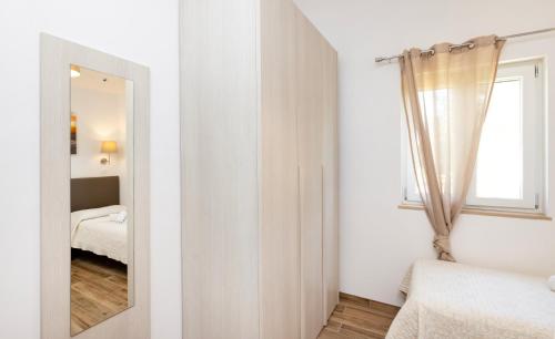 a white bedroom with a mirror and a window at Agriturismo I Tesori del Sud Vieste, Puglia in Vieste