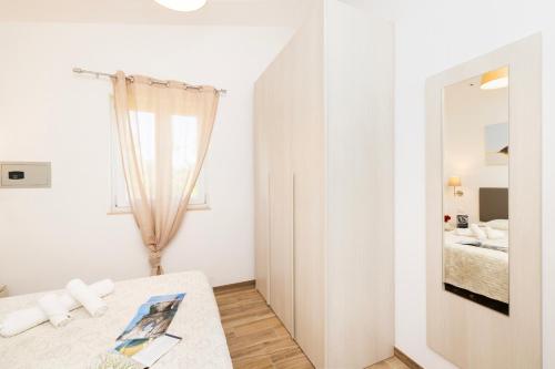 a white room with a bed and a mirror at Agriturismo I Tesori del Sud Vieste, Puglia in Vieste