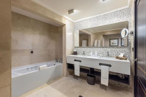 uma casa de banho com uma banheira e um espelho grande em Unique Club at Lopesan Costa Meloneras Resort em Maspalomas
