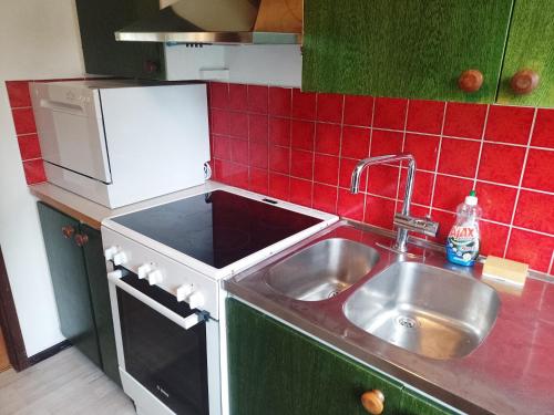 cocina con fregadero y pared de azulejos rojos en Holiday house in Grythem, Orebro, within walking distance to lake, en Örebro